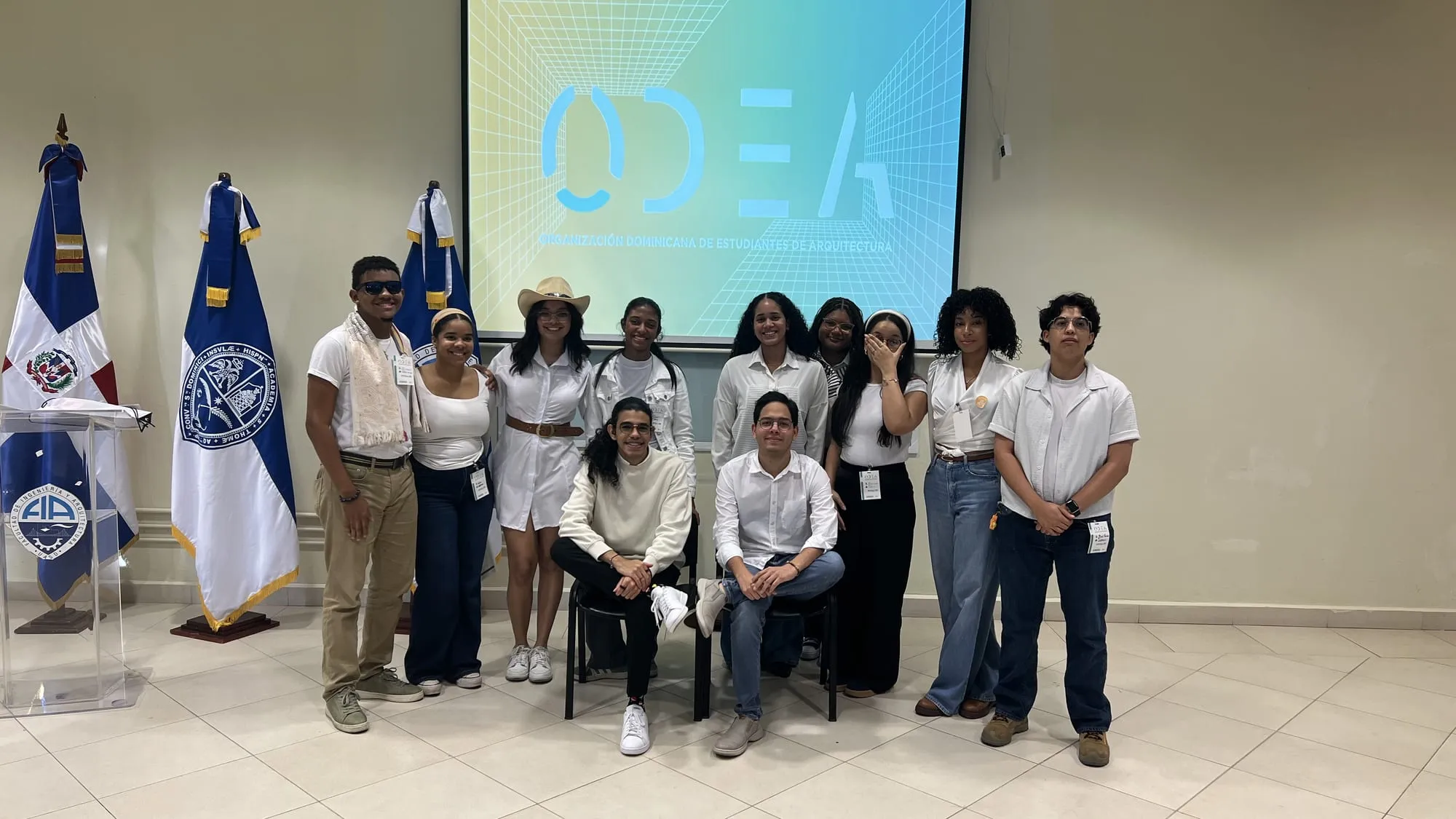 Estudiantes de arquitectura reunidos en la Asamblea Nacional de ODEA, frente al logotipo de la organización y las banderas dominicanas